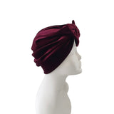 Burgundy headscarf with a flower on a mannequin head against a white background
