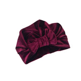 Maroon velvet headband with a large bow on a white background