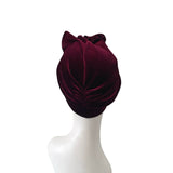 Maroon velvet turban on a mannequin head against a white background