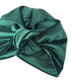 Green velvet turban with a knot on a white background