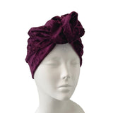 Purple velvet turban on a mannequin head against a white background
