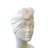 White turban with floral detail on a mannequin head against a white background