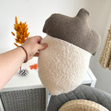 Hand holding a textured acorn-shaped pillow with a neutral background