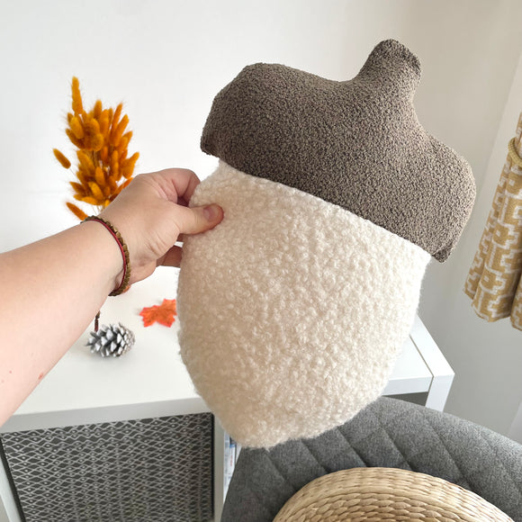 Hand holding a textured acorn-shaped pillow with a neutral background