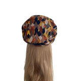 Multicolored patterned beret on a mannequin head with blonde hair against a white background