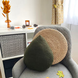 Gray armchair with decorative pillows and a small table with decor items in the background.
