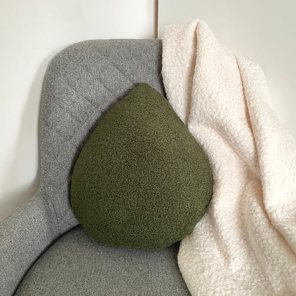Green textured pillow on a gray cushion with a white blanket