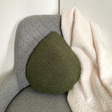 Green textured pillow on a gray cushion with a white blanket