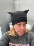 Person wearing a black cat-themed beanie with ears indoors.