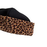 Close-up of a soft beanie hat showing a leopard print outer band and a black fleece inner lining, isolated on a white background.