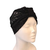 Black turban with lace details on a mannequin head against a white background