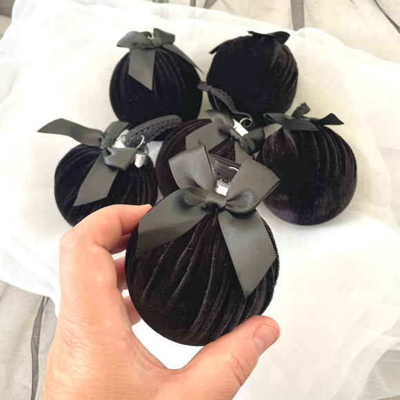 Black velvet ornaments with ribbons held by a hand on a white background