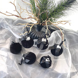 Black decorative ornaments with ribbons on a white fabric background