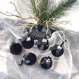 Black decorative ornaments with ribbons on a white fabric background