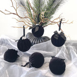 Black velvet ornaments with ribbons on a white fabric background