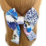Blue and white patterned hair bow on a person's head against a white background