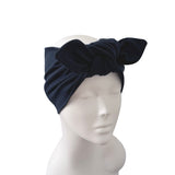 A dark navy blue velvet headband with a large bow, displayed on a white mannequin head against a plain white background.