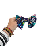 Hand holding a colorful bow with a tropical leaf pattern on a white background