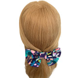 Colorful bow hair clip on a mannequin head with blonde hair against a white background