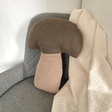 Decorative mushroom-shaped pillow on a gray chair with a white background