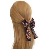 Leopard print hair bow on a mannequin head with blonde hair against a white background
