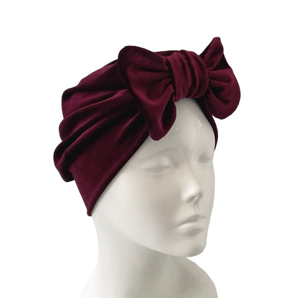 Burgundy headband with a large bow on a mannequin head against a white background