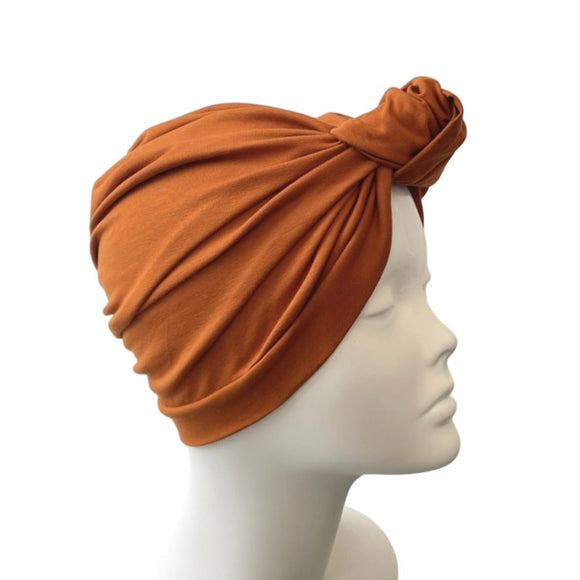 rust turban on a mannequin head against a white background