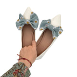 White shoes with floral bow details held by a hand on a white background