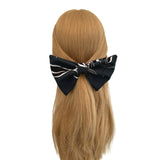 Black and white bow on a person's head with blonde hair against a white background