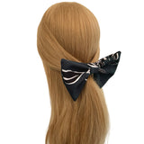 Black and white patterned hair bow on a person with blonde hair against a white background