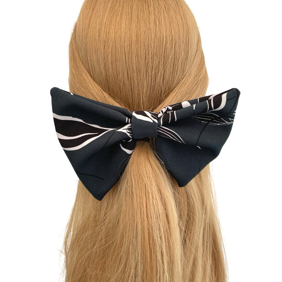 Black and white patterned hair bow on a person with blonde hair against a white background