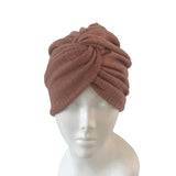 Brown knitted turban on a mannequin head against a white background