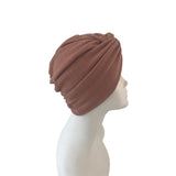 Brown turban on a mannequin head against a white background