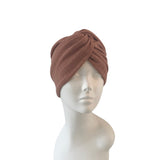 Brown knitted turban on a mannequin head against a white background
