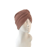 Brown knitted turban on a mannequin head against a white background