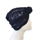 Navy blue lace turban on a mannequin head against a white background