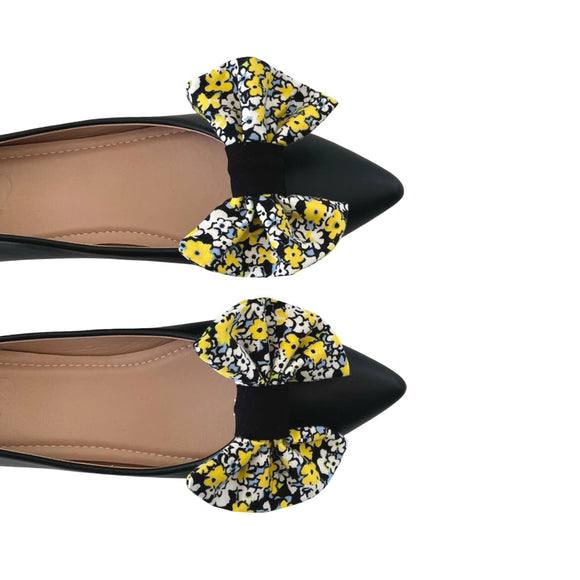 Black flats with floral bow details on a white background