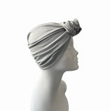 Gray turban with a floral accessory on a mannequin head against a white background