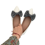 White shoes with gray bows worn by a person on a white background