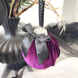 Purple ornament with a black bow hanging on a branch
