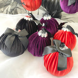 Decorative ornaments in rust, purple, and black with ribbons on a white surface.