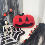 Halloween-themed decor with a jack-o'-lantern pillow, skeleton, and decorative beads on a black and white striped surface.