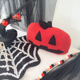 Knitted pumpkin decoration with Halloween-themed accessories on a white surface.