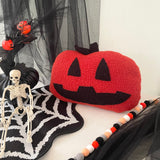 Halloween-themed decor with a red jack-o'-lantern pillow, skeleton, and spiderweb on a white background. ireland