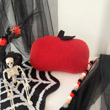 Red pumpkin pillow with a skeleton and decorative elements on a white surface.