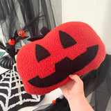 Red and black Halloween-themed pouch with a smiling face design, held in front of a festive background.