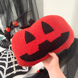 Red and black Halloween-themed pouch with a smiling face design, held in front of a festive background.