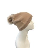 Beige beanie with faux fur pom-pom on a mannequin head against a white background