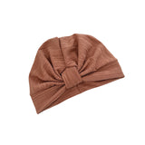 A ribbed knit turban hat in a warm brownish-rose or mauve tone, photographed on a plain white background.