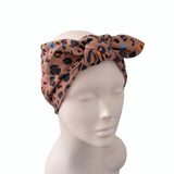 A leopard print fabric headband with a large bow, displayed on a white mannequin head against a plain white background.